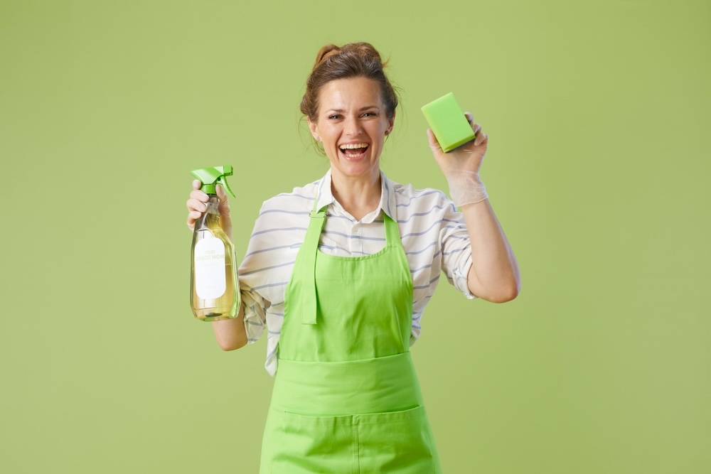 Female in a green apron holding organic carpet cleaner products